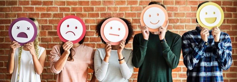 Menschen, die sich ausgedruckte Smilie-Gesichter vor den Kopf halten