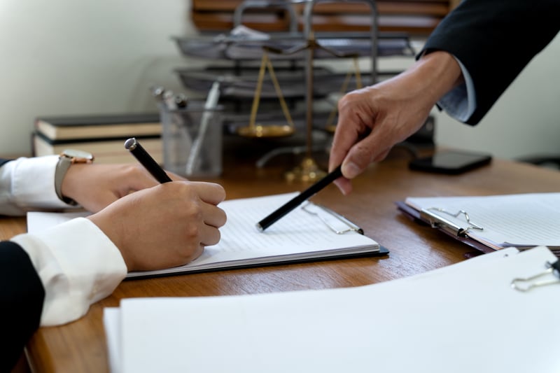 Klemmbrett mit Papier jemand zeigt mit Stift auf die Felder