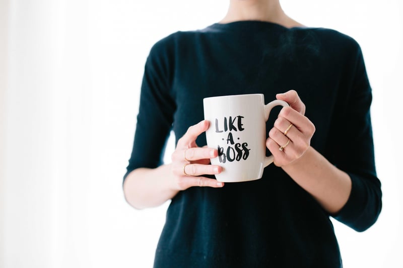 Frau hält Tasse in der Hand mit Aufschrift „Like a Boss”