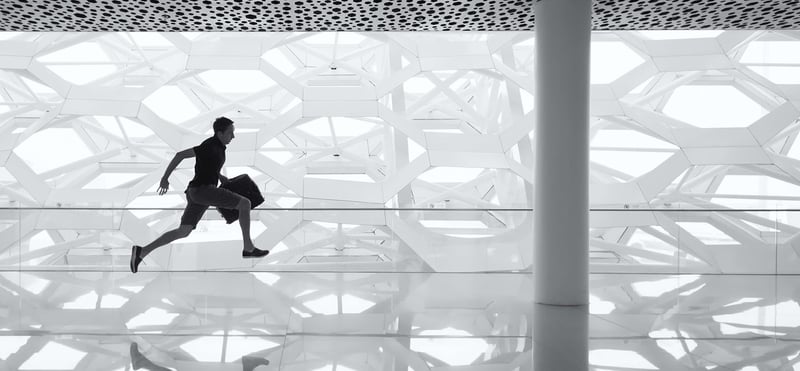 Mensch als Schattensilhouette springt über moderne Glas-Architektur