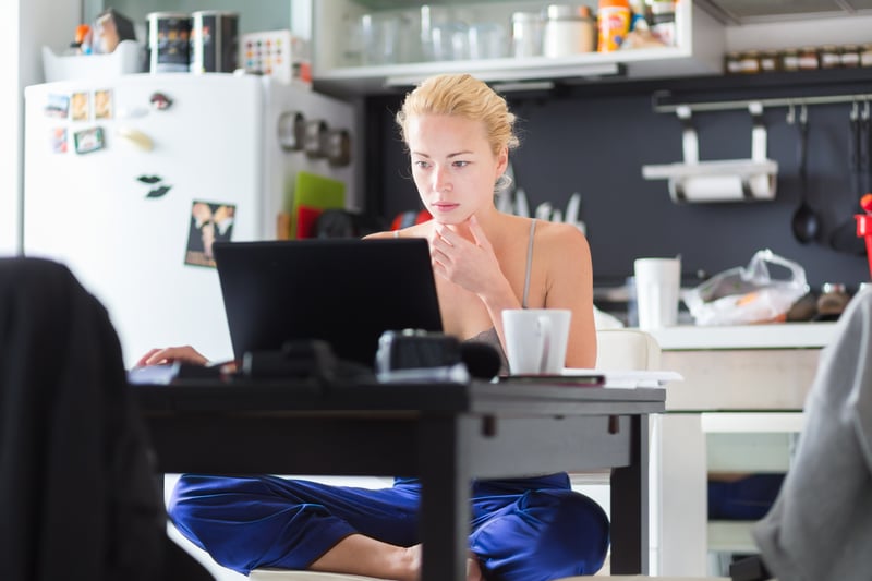 Frau arbeitet am Küchentisch mit Laptop