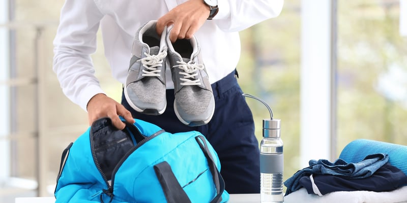 Geschäftsmann packt Sportsachen auf dem Schreibtisch ein