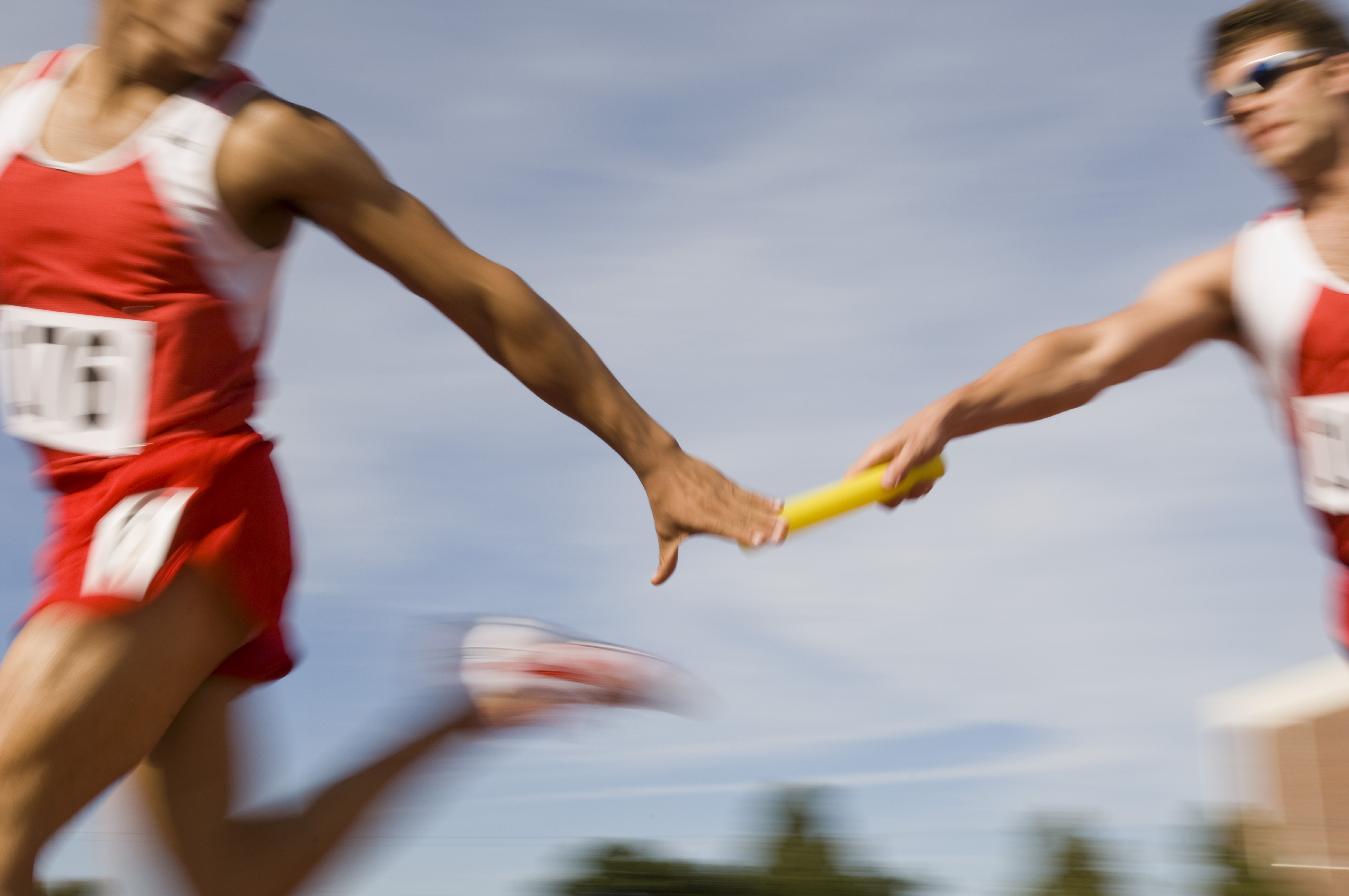 Leichtathleten bei Übergabe eines Staffelstabes