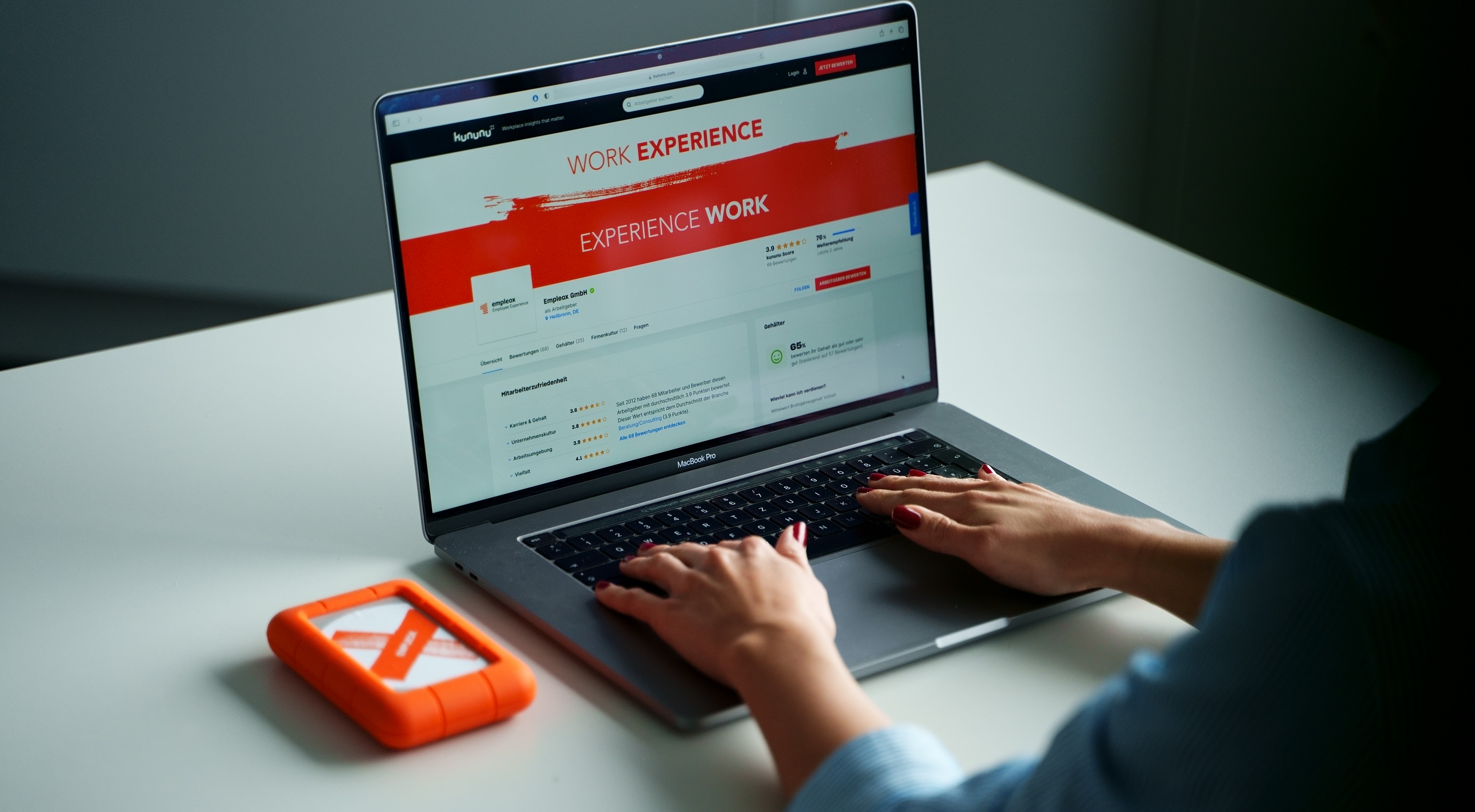 Person sitzt vor Laptop und hat ein Kununu Firmenprofil geöffnet