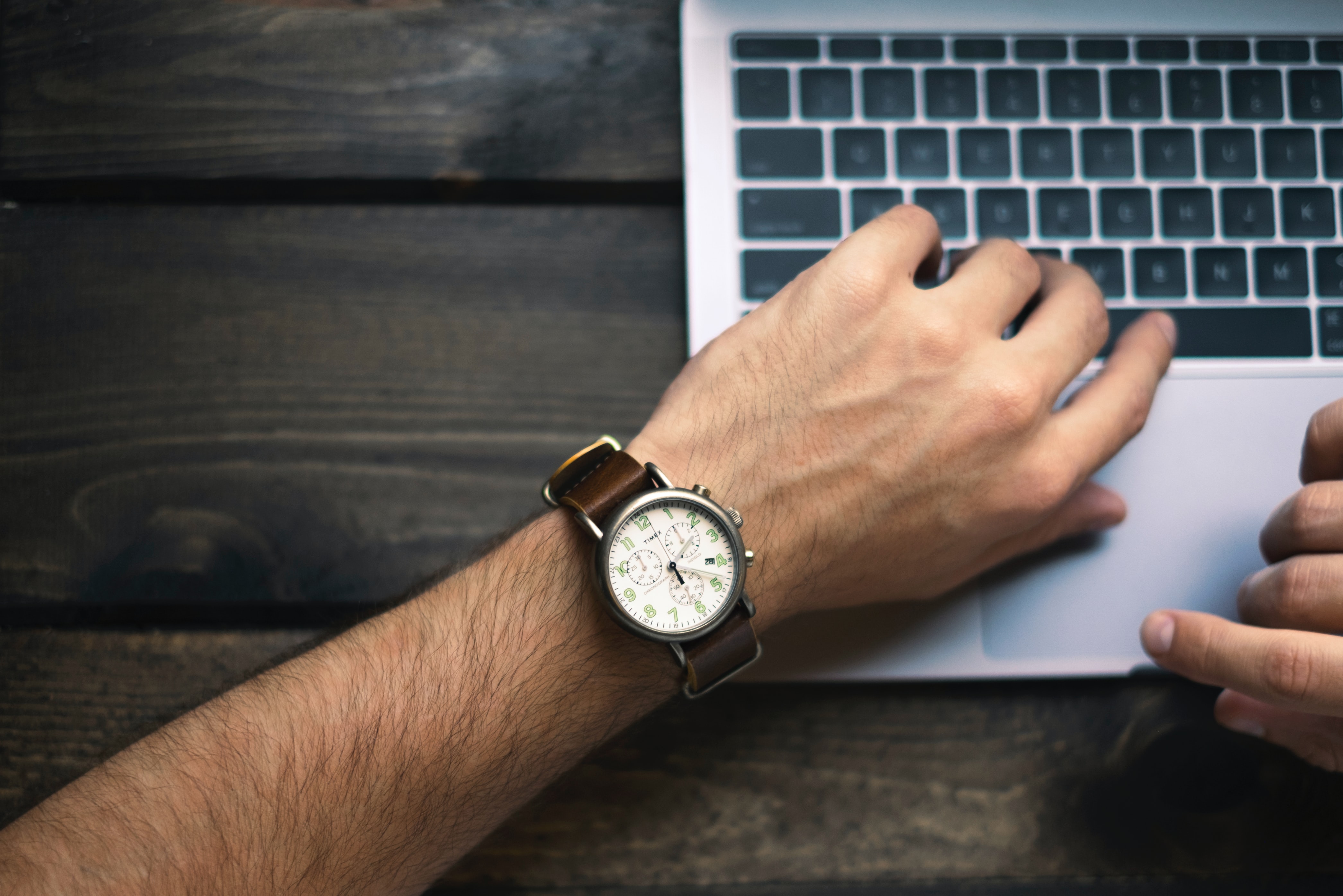 Hand mit Armbanduhr auf Laptoptastatur