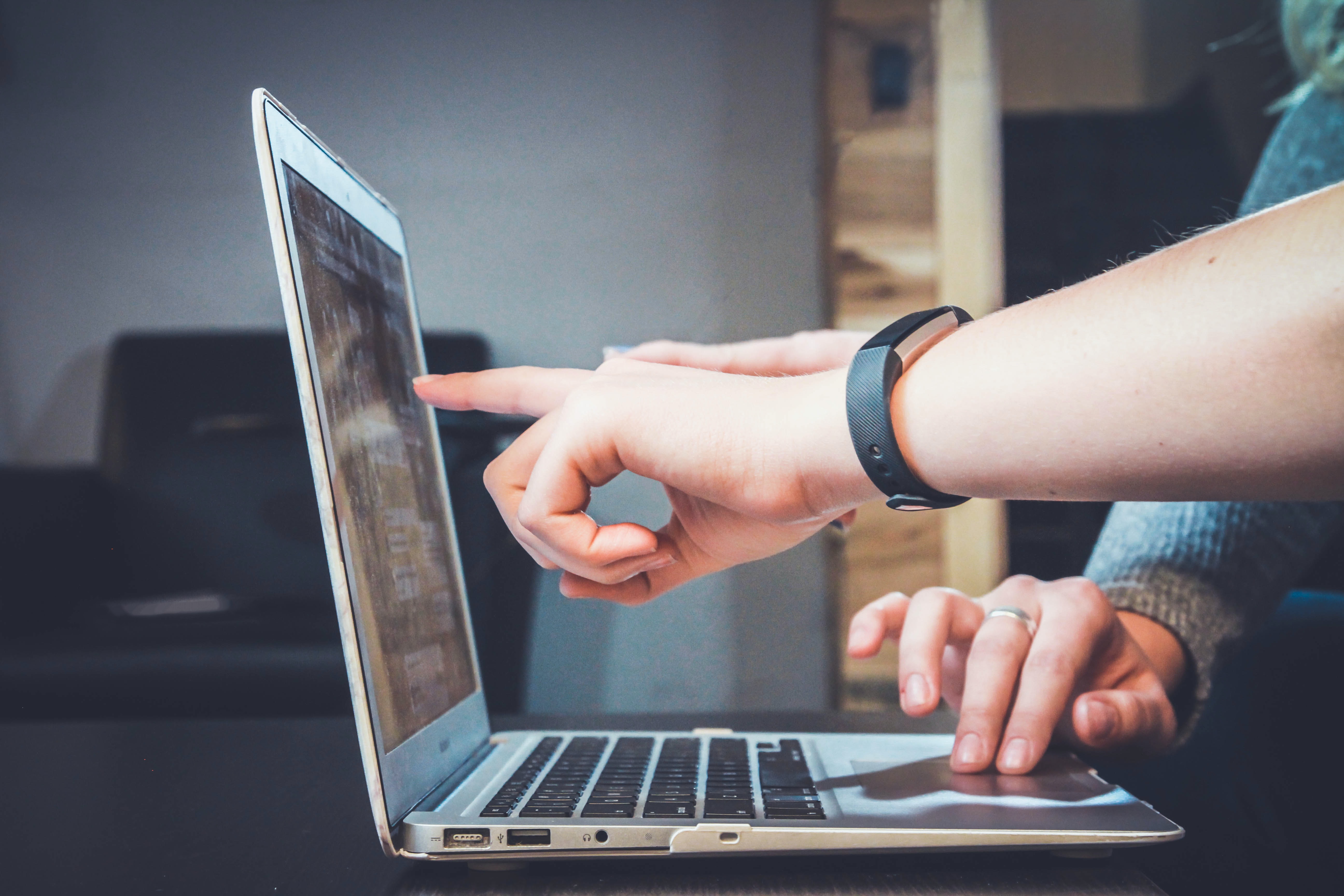 Hände zeigen auf Laptop-Bildschirm