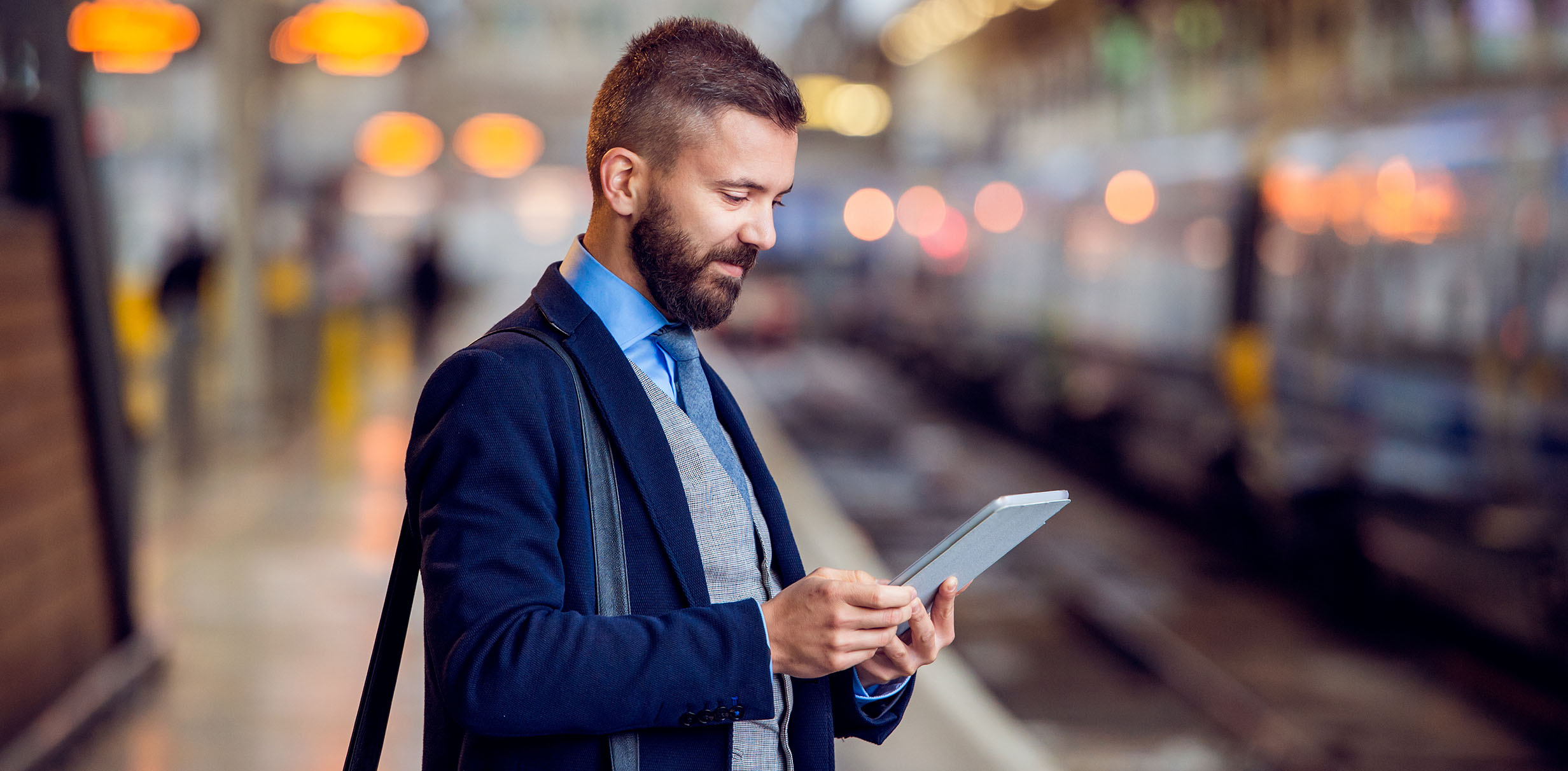 Geschäftsreisender am Bahnhof mit Tablet in der Hand